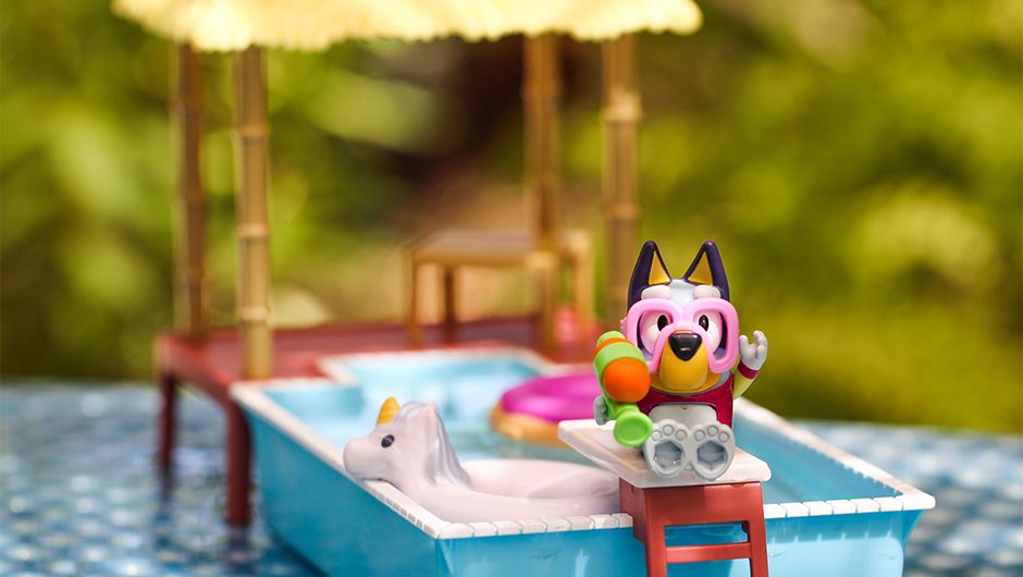 Lifestyle photograph of the toy with Bluey figurine sat on the pool playset with the pool in the background.