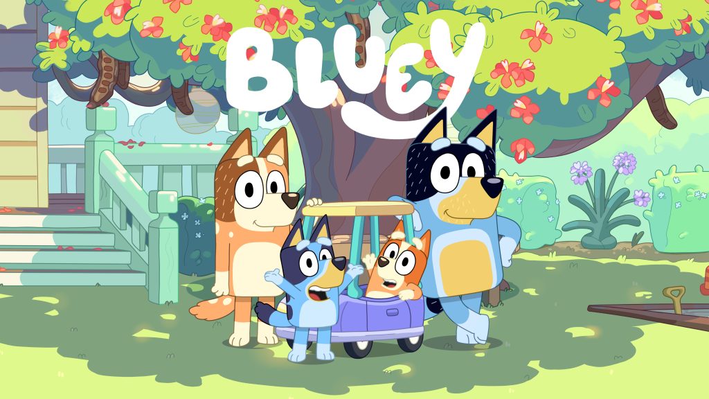 Bluey and her family gather around Bingo sitting in Pedley under a flowering tree in a garden.
