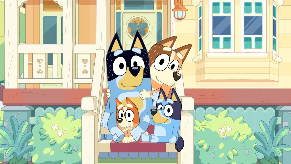 Bluey and her family sit together on a porch in front of their home, smiling in a relaxed setting.