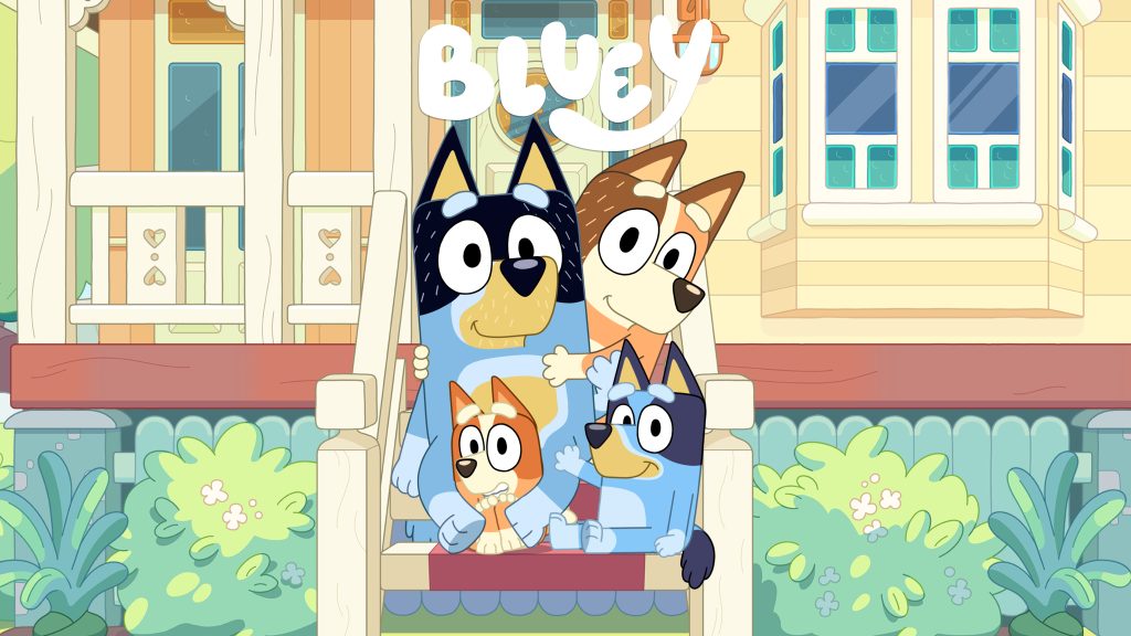 Bluey and her family sit together on a porch in front of their home, smiling in a relaxed setting
