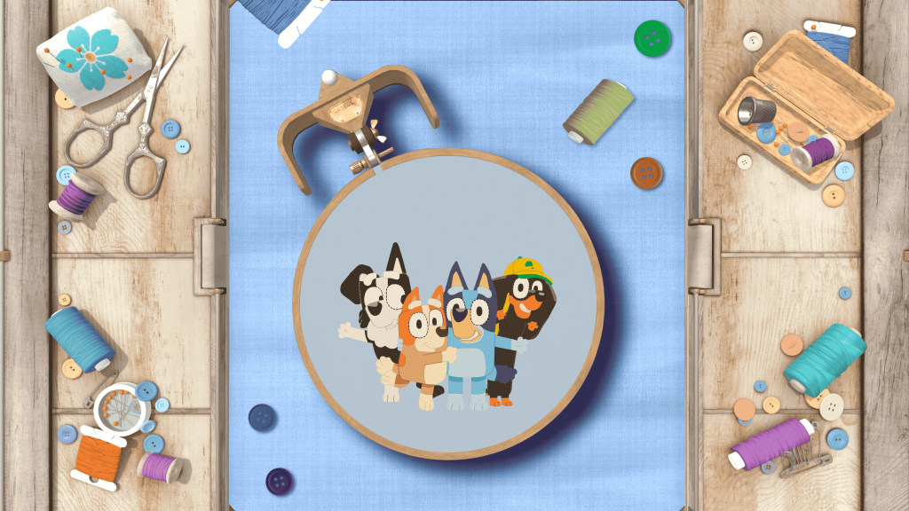 Stitch hoop featuring Bluey, Bingo and friends stitched onto fabric, surrounded by sewing supplies.